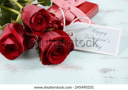 Vintage red roses gift for Valentines Day, birthday or special occasion on pale aqua blue recycled distressed wood background, with greeting card.