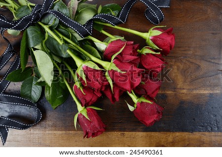 Happy Valentine\'s Day red roses on dark recycled wood background - overhead with black ribbon.