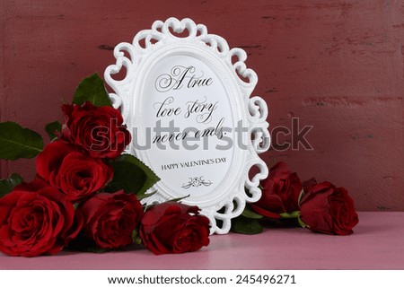 Happy Valentines Day romantic vintage style white photo frame against red and pink rustic wood background with bouquet of red roses, with A True Love Story Never Ends sample text.