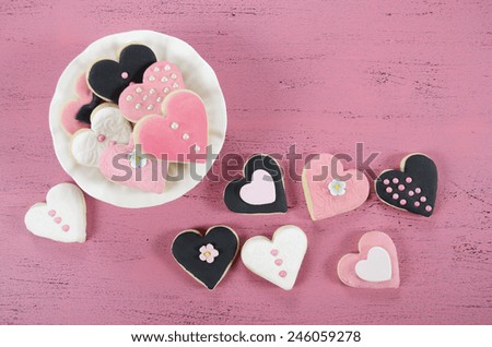 Pink, black and white homemade heart shape cookies on vintage shabby chic pink wood background for Valentines Day, wedding, Mothers Day or female birthday, with copy space.