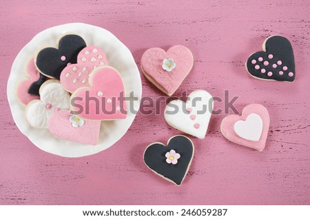Pink, black and white homemade heart shape cookies on vintage shabby chic pink wood background for Valentines Day, wedding, Mothers Day or female birthday.