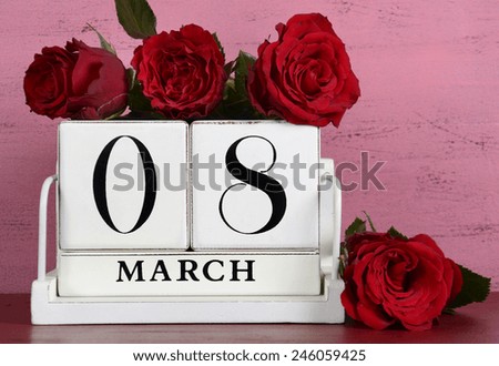 Vintage white wood calendar for March 8, International Womens Day, with red roses on shabby chic pink and red background, closeup.