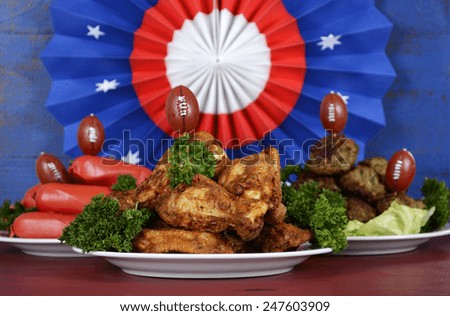 Super Bowl Sunday football party celebration food plates with chicken buffalo wings, meat balls, hot dogs and USA party decorations.