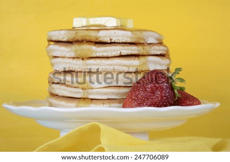 Shrove Pancake Tuesday stack of pancakes with honey and butter on yellow and aqua blue vintage shabby chic table, closeup.