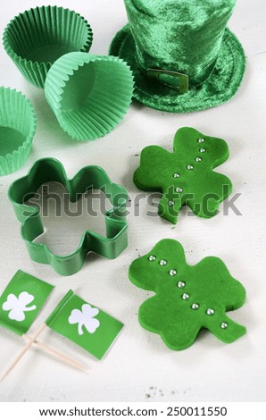 Happy St Patricks Day cooking and baking concept with green cupcake pans and shamrock cookie cutter  on vintage style white wood table.