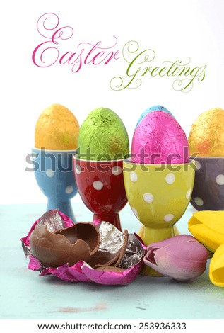 Happy Easter chocolate eggs wrapped in bright color foil in red, yellow, blue, green and purple polka dot egg cups, vertical with sample text.