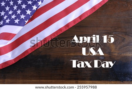 April 15, USA Tax Day reminder on dark recycled wood background with American stars and stripes flag.