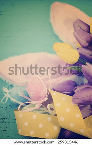 Easter Bunny Ears with yellow and purple tulips on green background with applied retro vintage filter.