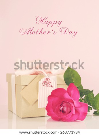 Happy Mothers Day gift of kraft paper gift box with a pink rose, and applied retro vintage style filters and faint light stream.