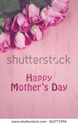 Happy Mothers Day gift of fresh pink roses on a pink distressed wood background with sample text, and applied retro vintage style filters.