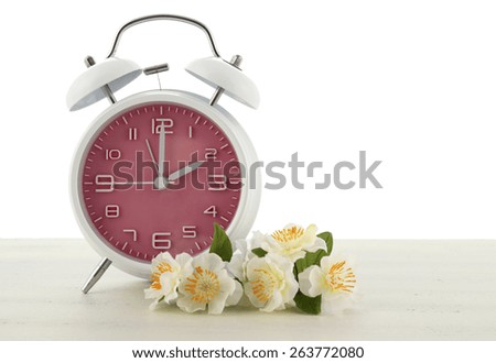 Daylight Saving Time concept with spring theme pink retro style alarm clock on white wood background.