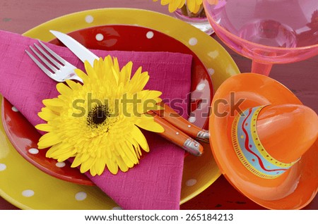 Happy Cinco de Mayo bright colorful party table place setting with bright gerbera daisy flowers on distressed red wood table.