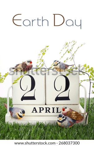 Earth Day, April 22, Concept with vintage wood calendar and small birds and fern on grass background.