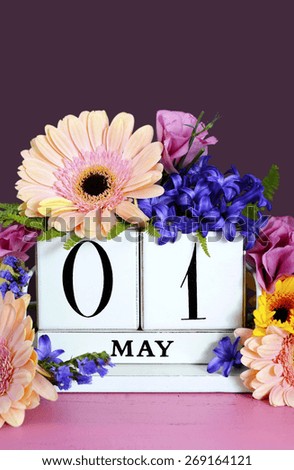 Happy May Day vintage wood calendar decorated with Spring flowers on pink wood table with dark purple background.