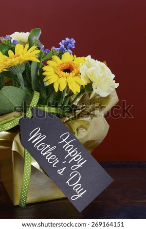 Happy Mothers Day gift of Spring Flowers on dark wood table and rustic dark red background.