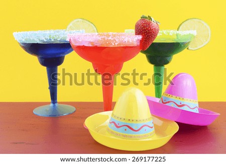 Happy Cinco de Mayo colorful party theme with bright color margarita drinks on red wood table and yellow background.