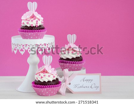 Happy Mothers Day pink and white cupcakes on retro style cake stands on vintage white wood table.