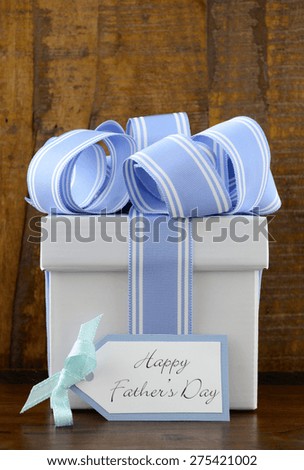 Happy Fathers Gift with blue and white gift on wood background, and greeting tag.