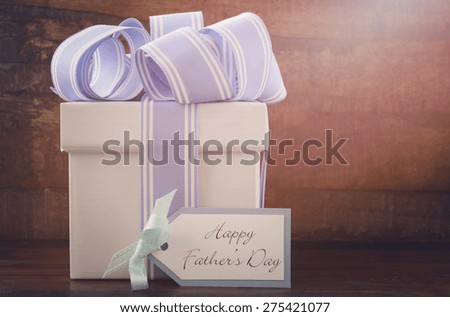Happy Fathers Gift with blue and white gift on wood background,  with applied retro filters and lens flare sun beam.