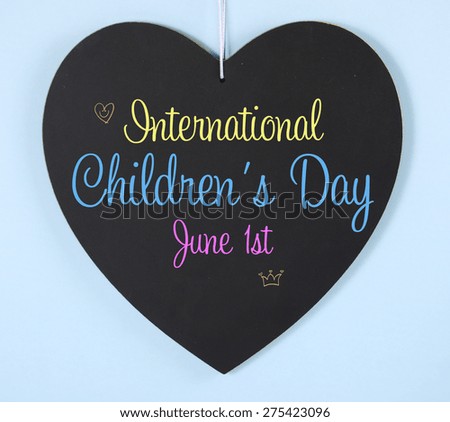 International Childrens Day message greeting on heart shape blackboard sign on pale blue background.