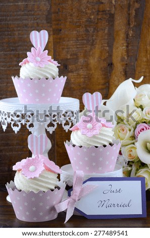 Wedding Day shabby chic style pink cupcakes on dark recycled vintage wood background.