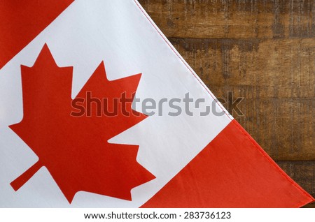Canadian red and white maple leaf flag against dark wood rustic background for Canada Day, July 1, celebration and national holidays.
