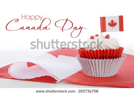 Happy Canada Day celebration cupcake with red and white Canadian maple leaf flag on white wood table, and sample text.