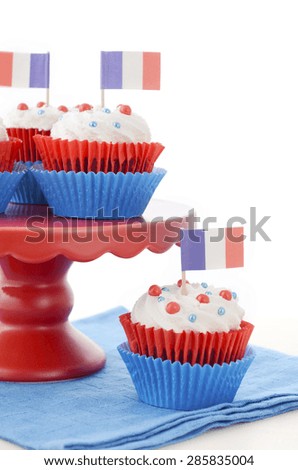 Red, white and blue theme cupcakes on white wood table for Bastille Day or French party celebration.