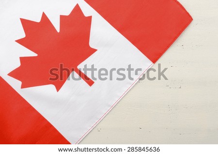 Canadian red maple leaf flag on white wood shabby chic table with copy space for your text here.