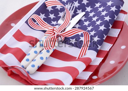 Patriotic table place setting with USA flag and polka dot plate on white wood shabby chic table for Fourth of July and USA holiday and events celebration.