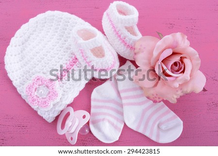 Its a Girl Baby Shower or Nursery layout with bonnet, booties, socks and silk rose on pink shabby chic table.