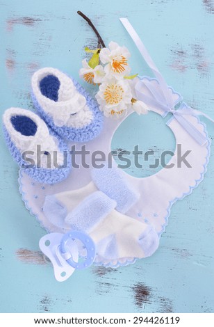 Its a Boy Baby Shower or Nursery layout with bonnet, booties, socks and pacifier and dummy on pale blue shabby chic table.