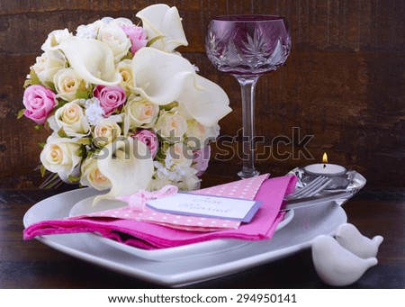 Pink Theme Wedding Table Place Setting with white heart shape plates and floral bouquet on dark rustic wood background.