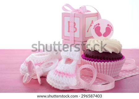 Its a Girl Baby Shower Cupcakes with baby feet toppers and decorations on shabby chic pink wood table.