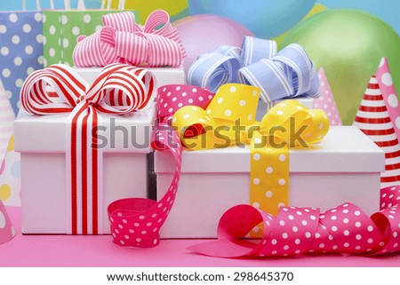 Bright colorful party table with balloons, streamers, party favor gift bags and gifts with bright color ribbons and bows.