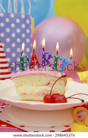 Bright colorful Happy Party Table with balloons, streamers, party favor gift bags with slice of cake and lit candles spelling party.