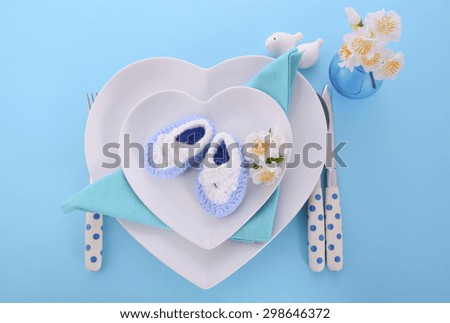 Its a Boy blue theme baby shower table place setting with heart shape plates on blue table background.