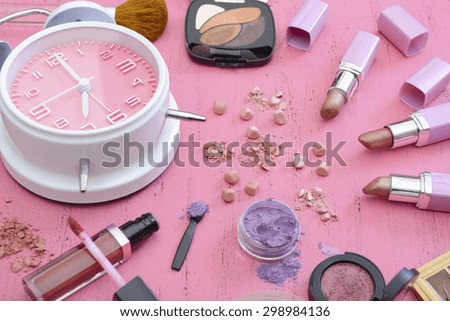 Early morning makeup routine and products on vintage shabby chic pink wood table.