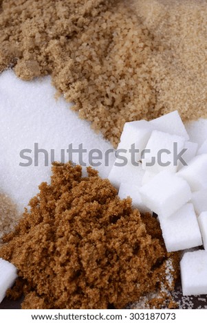 Different types of sugar including white, brown, dark brown, demerara, coffee sugar crystals and sugar cubes.