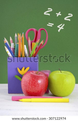 Back to school or education concept with colorful purple pencil box against green chalkboard.