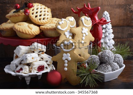 Traditional Christmas sweets and party food. spotlighted in festive setting with rustic style gifts and decorations on dark vintage wood background.