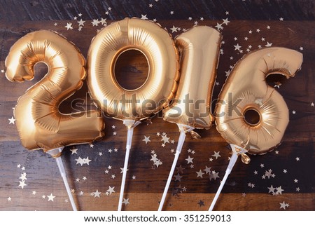 Happy 2016 gold New Year Balloons with glitter stars on dark wood table background.