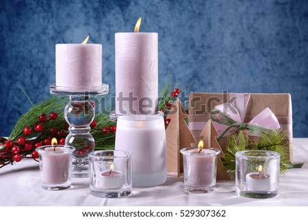 Festive glamorous holiday Christmas table setting with pink candles, gift against a blue background.