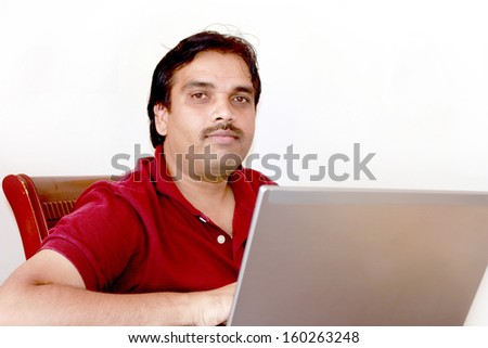 Isolate image of an Indian middle age successful happy man with Laptop and this represents a concept of working from home, online sales, operating online business, checking data , mails in internet