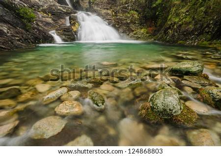 Mountain waterfall, stream of water in forest and mountain terrain.