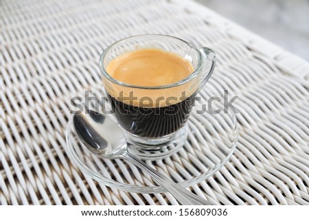 Shot of espresso on white rattan table.