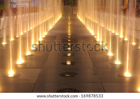 Multiple Jets Of Water In A Fountain, Lighting Show On Ground In Night Time.