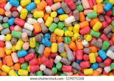 Abstract background of small cylindrical colorful plastic pellets in the colors of the rainbow or spectrum in a random scattered pattern