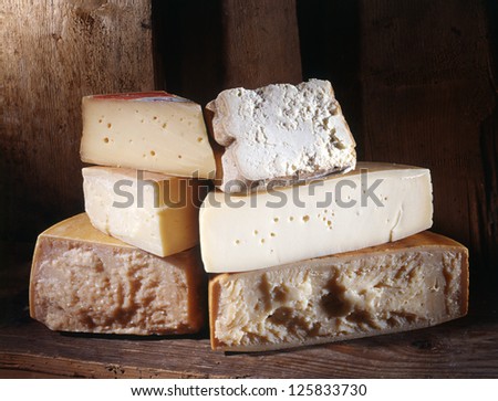 Selection of different cut cheeses at a market store or in a rural kitchen piled on top of one another in a display