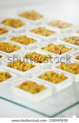 Individual ceramic dishes of spicy couscous displayed on a buffet table at a catered event